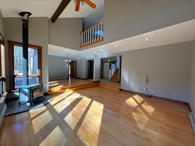 80 Mill St, Conway, NH 03813 - unfurnished living room featuring a wood stove, stairs, a ceiling fan, light wood finished floors, and high vaulted ceiling