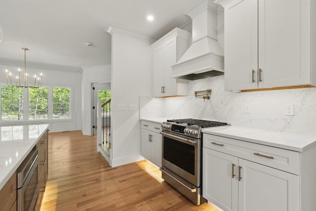 286 S Rd, Brentwood, NH 03833 - kitchen with stainless steel appliances, custom range hood, ornamental molding, light wood-style floors, and a chandelier