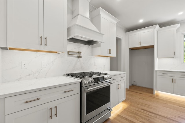 286 S Rd, Brentwood, NH 03833 - kitchen with gas stove, premium range hood, white cabinetry, light wood finished floors, and backsplash