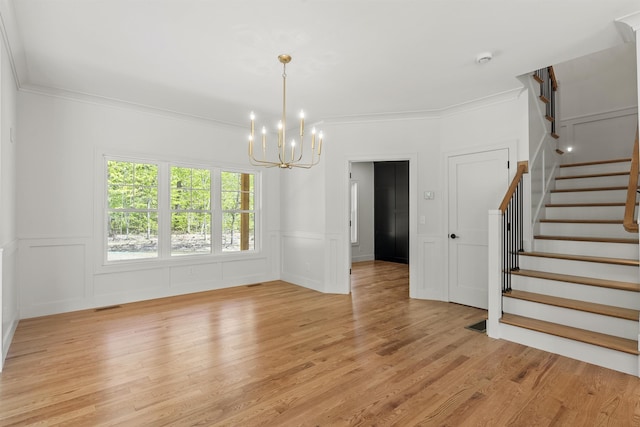 286 S Rd, Brentwood, NH 03833 - unfurnished living room with a chandelier, stairs, light wood-type flooring, crown molding, and a decorative wall