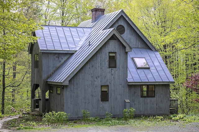 258 Densmore Hill Rd, Hartland, VT 05048 - view of home's exterior with a standing seam roof, metal roof, a chimney, and a forest view