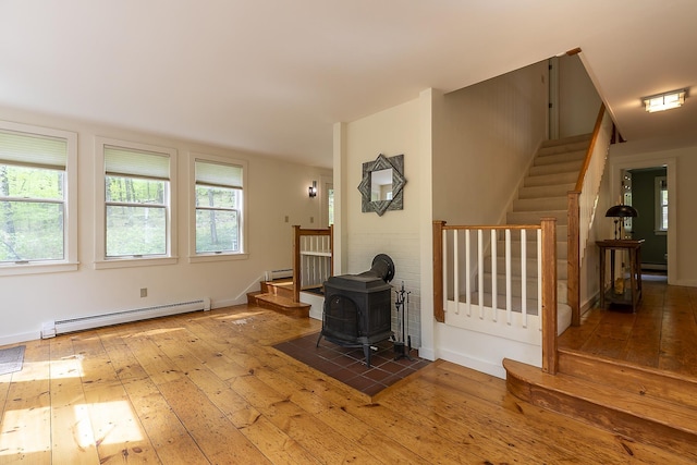 258 Densmore Hill Rd, Hartland, VT 05048 - living area featuring baseboard heating, wood-type flooring, stairway, and a wood stove