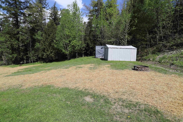 412 Covered Bridge Rd, Irasburg, VT 05845 - view of grassy yard featuring an outdoor fire pit, an outbuilding, and a storage unit