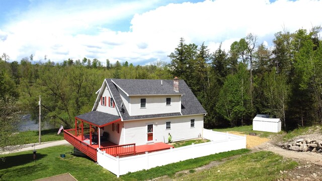 412 Covered Bridge Rd, Irasburg, VT 05845 - back of property with a deck, a storage unit, an outdoor structure, a shingled roof, and a wooded view