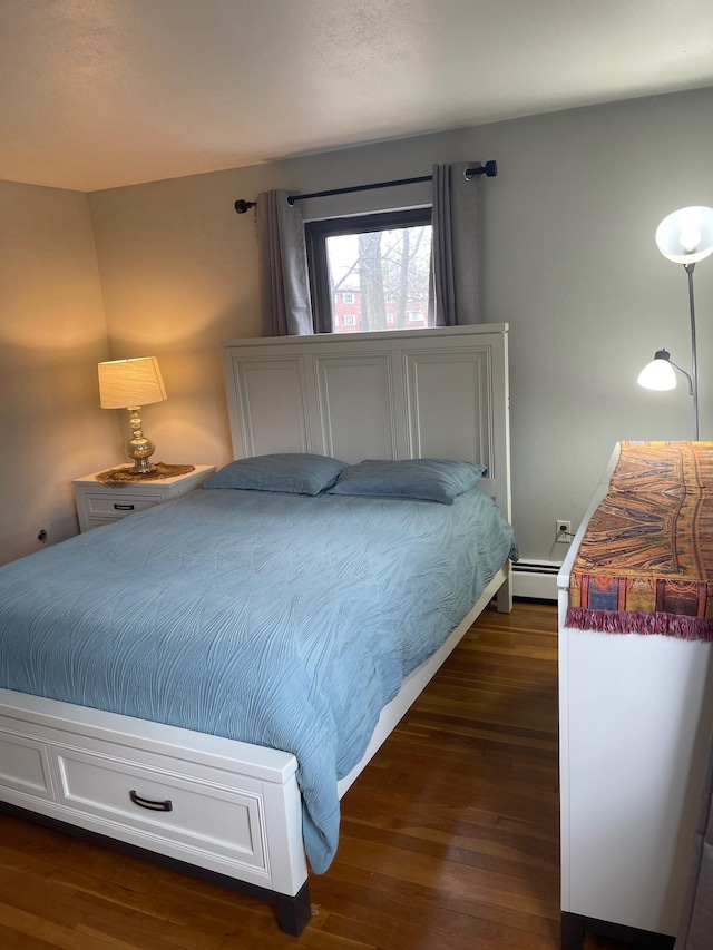bedroom featuring a baseboard heating unit and dark wood-style floors