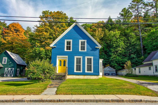56 Andover St, Ludlow, VT 05149 - view of front facade with an outbuilding, a front lawn, and a garage