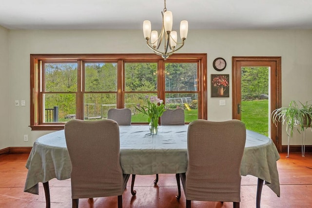 dining space featuring a chandelier, baseboards, and wood finished floors