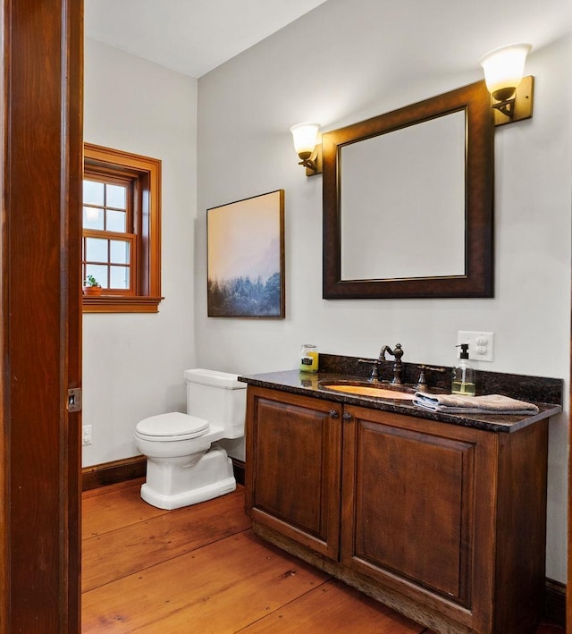 bathroom with hardwood / wood-style flooring, toilet, vanity, and baseboards