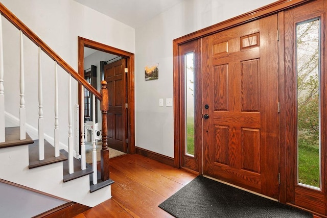 foyer with stairway, hardwood / wood-style floors, plenty of natural light, and baseboards