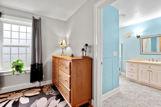 bedroom featuring a sink, multiple windows, and baseboards