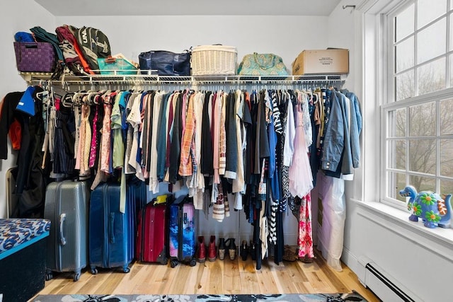 spacious closet with a baseboard heating unit and wood finished floors