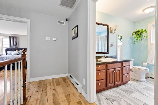 bathroom featuring a baseboard heating unit, vanity, and toilet