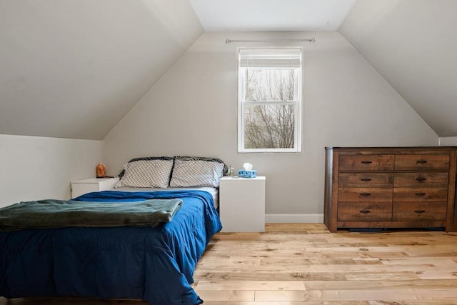 bedroom with light wood-style floors, vaulted ceiling, and baseboards
