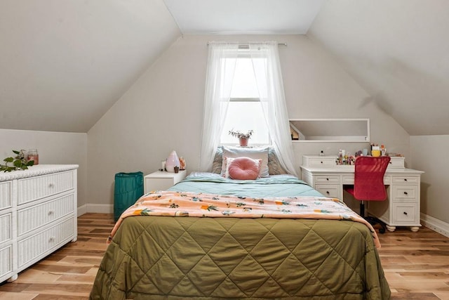 bedroom featuring light wood-style floors, vaulted ceiling, and baseboards