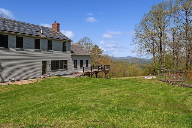 view of grassy yard with a deck with mountain view