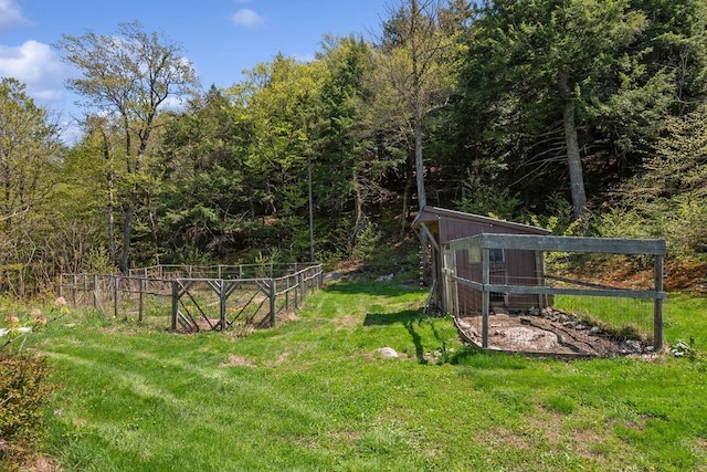 view of yard featuring exterior structure, an outbuilding, and a wooded view