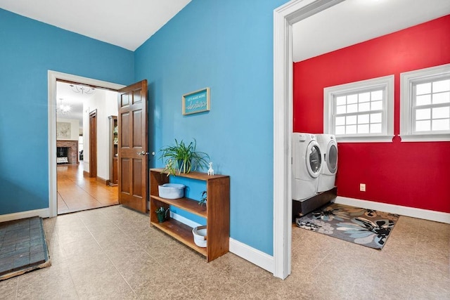 laundry room featuring washing machine and clothes dryer, a fireplace, and baseboards
