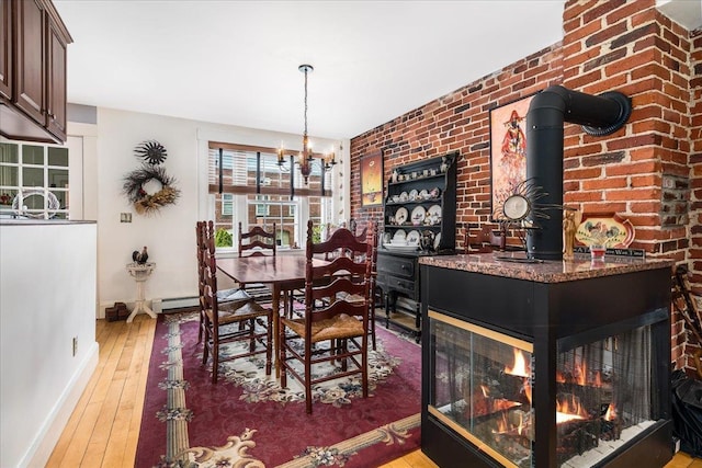 67 Kidder St, Manchester, NH 03101 - dining area with baseboards, wood-type flooring, a chandelier, a baseboard radiator, and brick wall
