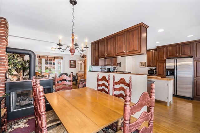 67 Kidder St, Manchester, NH 03101 - dining room featuring a chandelier, recessed lighting, light wood-style flooring, and a wood stove