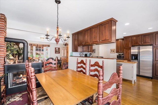 67 Kidder St, Manchester, NH 03101 - dining area featuring a chandelier, recessed lighting, light wood-style floors, and a wood stove