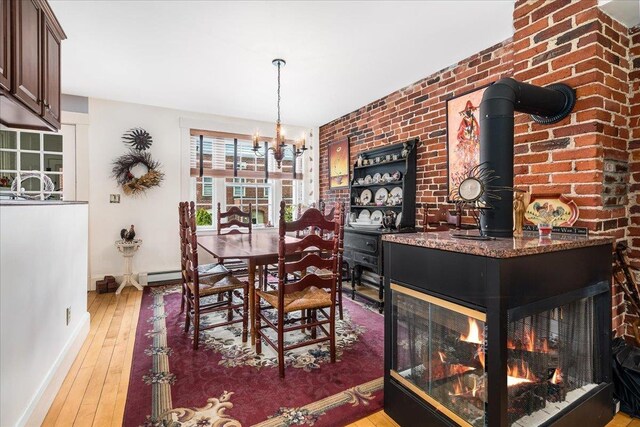 67 Kidder St, Manchester, NH 03101 - dining space featuring baseboards, wood-type flooring, a chandelier, a baseboard radiator, and a wood stove