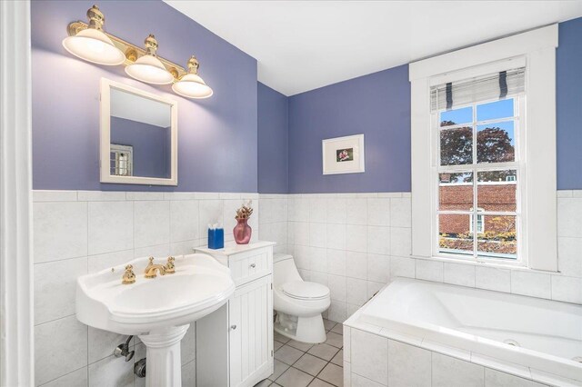 67 Kidder St, Manchester, NH 03101 - bathroom with tile walls, a garden tub, plenty of natural light, toilet, and tile patterned flooring