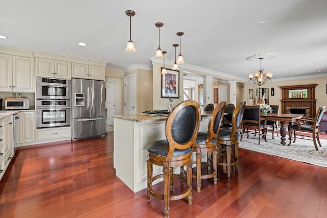25 Golden Gate Dr, Hooksett, NH 03106 - kitchen featuring stainless steel appliances, cream cabinetry, dark wood-type flooring, ornamental molding, and light stone countertops