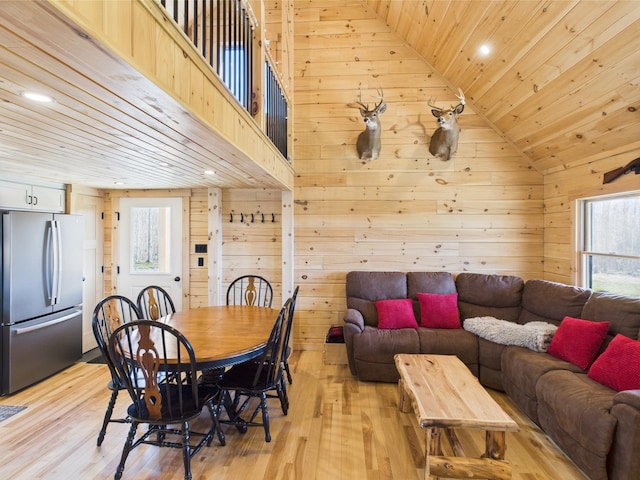 dining room featuring wood ceiling, wood walls, recessed lighting, lofted ceiling, and light wood-style floors