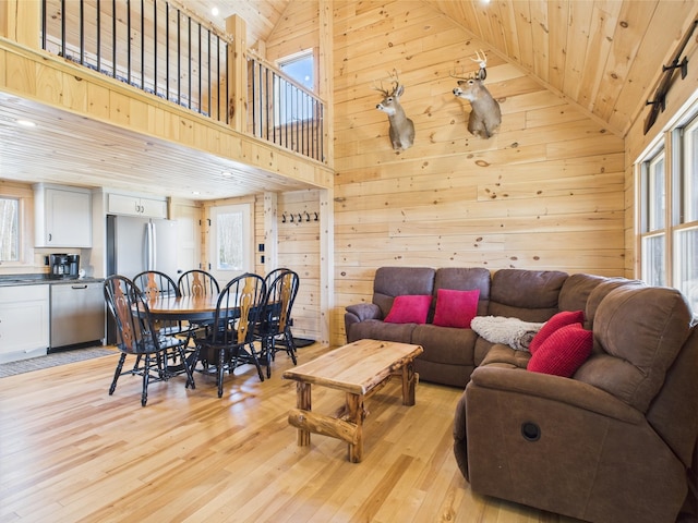 living room with wood ceiling, light wood-style flooring, wooden walls, and high vaulted ceiling