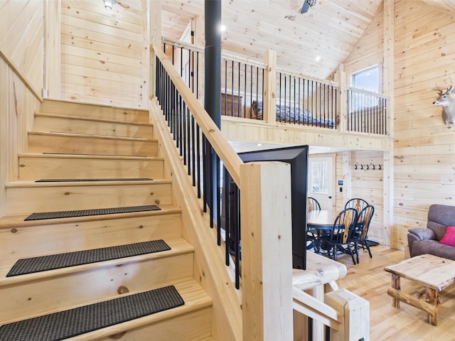 staircase featuring high vaulted ceiling, wood finished floors, wood walls, and wooden ceiling