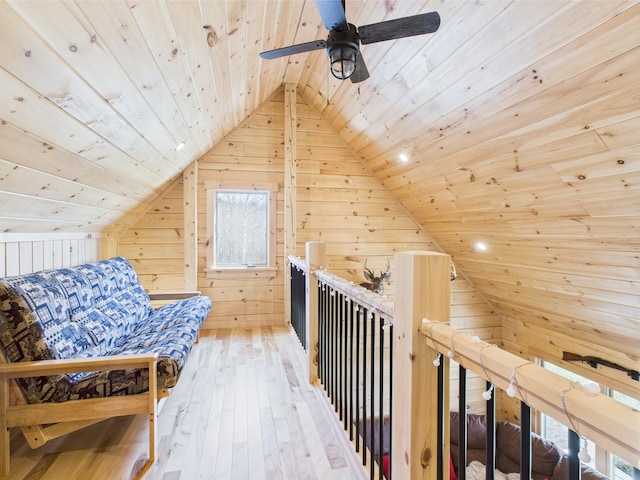 living area with wood ceiling, wood walls, lofted ceiling, hardwood / wood-style flooring, and a ceiling fan