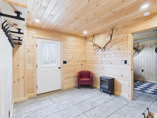 foyer entrance with wood ceiling, wood walls, recessed lighting, wood finished floors, and a wood stove