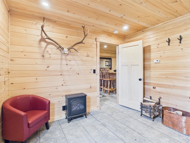 sitting room featuring wood walls, wood ceiling, a wood stove, recessed lighting, and wood finished floors