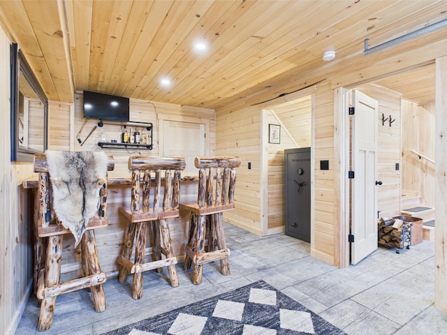 dining room featuring a bar, wood walls, wooden ceiling, recessed lighting, and baseboards