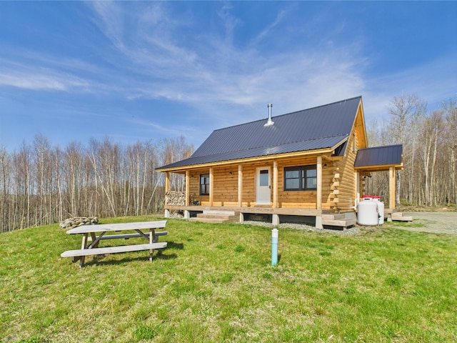 back of house featuring a porch, log exterior, metal roof, and a yard