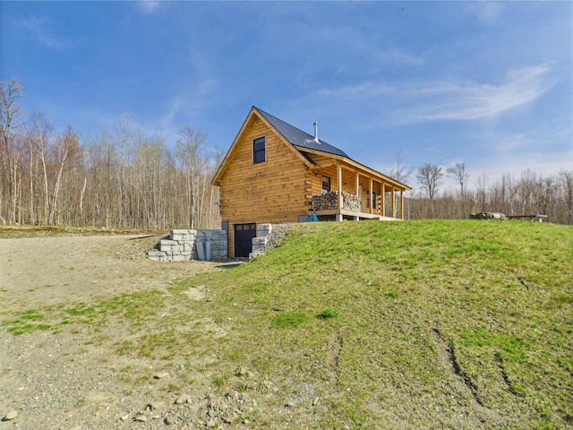 view of side of home featuring log exterior, an attached garage, and metal roof