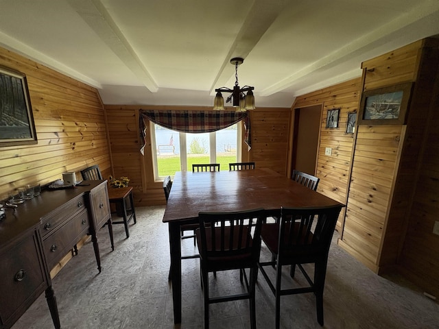 dining space with wooden walls and a chandelier