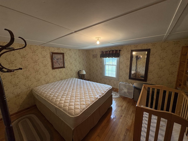 bedroom featuring hardwood / wood-style flooring, wallpapered walls, and baseboards