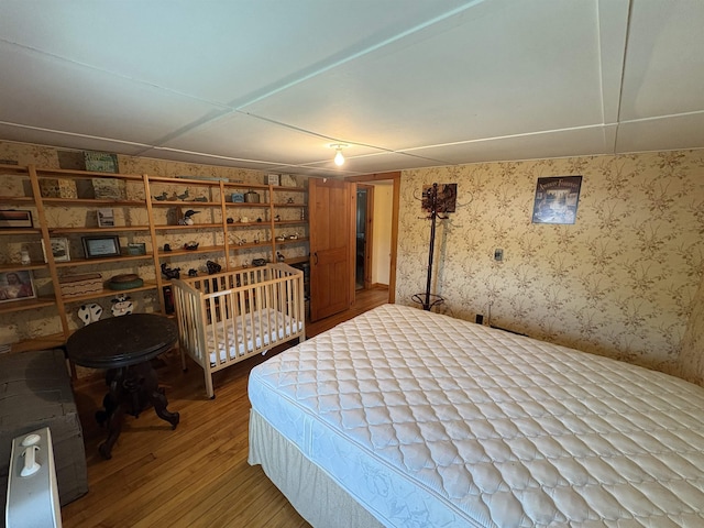 bedroom with wallpapered walls and light wood finished floors
