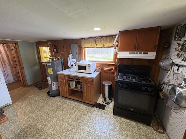 kitchen with black range with gas cooktop, electric water heater, white microwave, under cabinet range hood, and brown cabinets