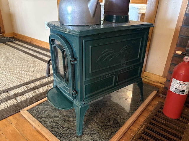 detailed view of baseboards, a wood stove, and wood finished floors