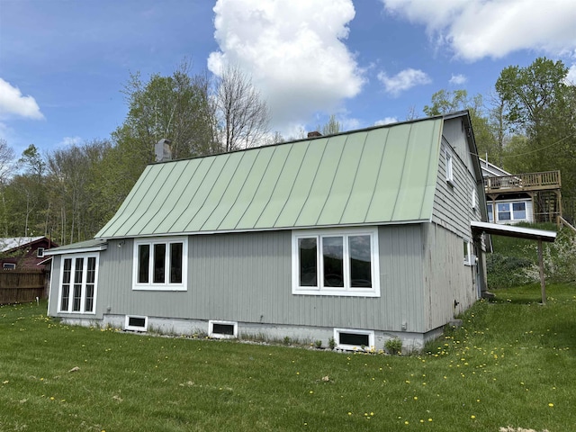 view of side of home featuring a standing seam roof, a yard, metal roof, and a chimney