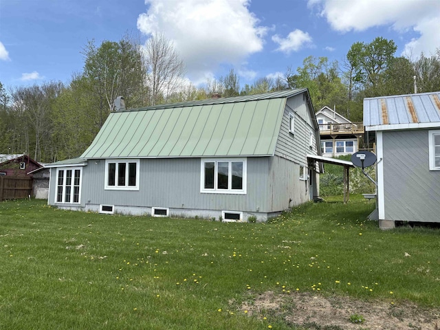 back of house with a standing seam roof, a lawn, and metal roof