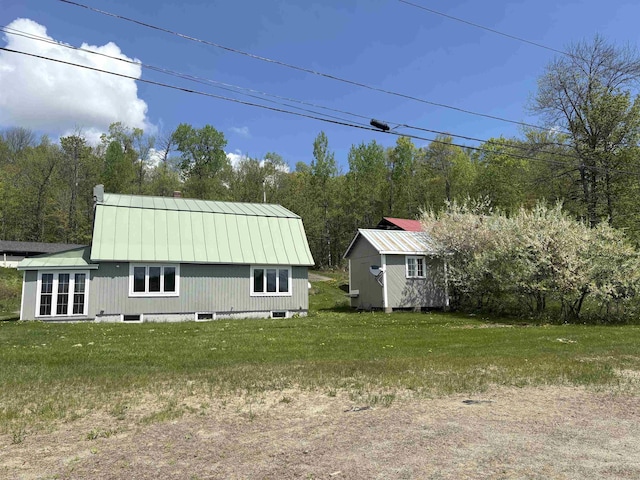 view of property exterior featuring metal roof, a lawn, an outbuilding, and a storage unit