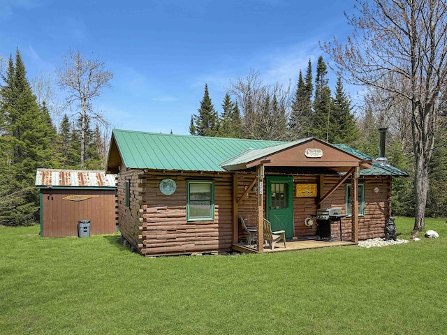 log home with a front lawn, metal roof, log siding, and an outbuilding