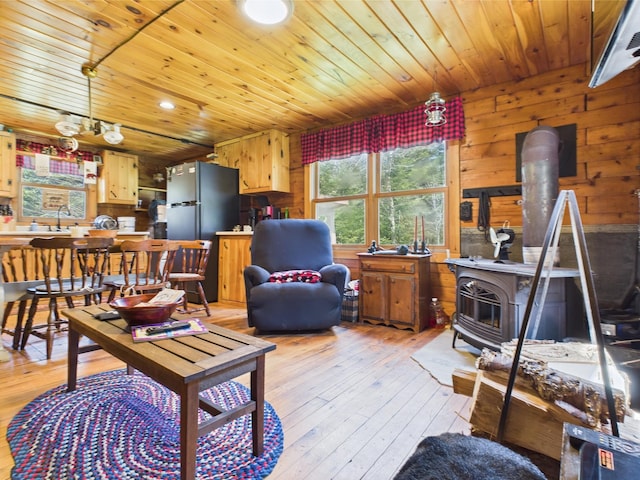 living area featuring a wood stove, light wood finished floors, wood ceiling, and recessed lighting