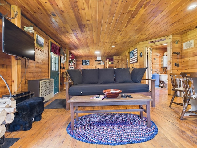 living area featuring wooden walls, hardwood / wood-style floors, wooden ceiling, and water heater