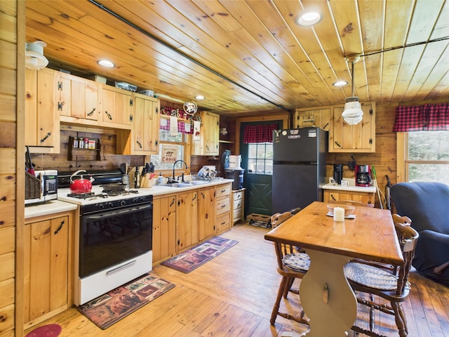 kitchen with stainless steel appliances, light countertops, a sink, wooden ceiling, and healthy amount of natural light