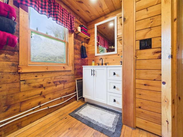 bathroom featuring wooden walls, wood-type flooring, vanity, and wooden ceiling