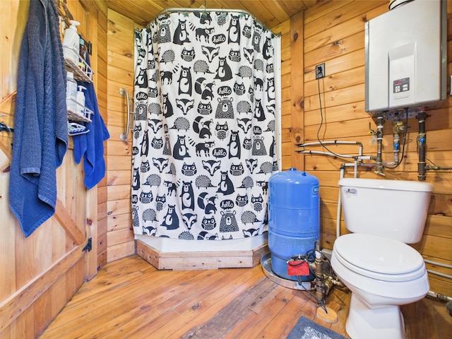 bathroom with wooden walls, water heater, hardwood / wood-style flooring, a stall shower, and toilet